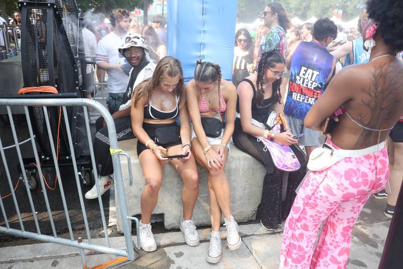 Taylor Him, left, and Mannah Mily from Hinsdale, relax at a mist blowing fan at Lollapalooza on Saturday, Aug. 3, 2024 in Chicago.