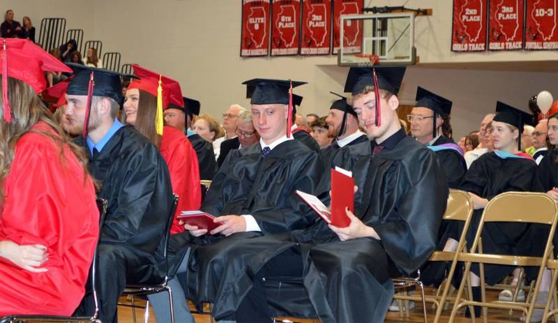 Dyllan Schreiber, right, looks at his diploma after walking across the stage during the Forreston High School Class of 2023 commencement on May 14, 2023. To his left is Jayden Zink. Schreiber is going into the workforce. Zink plans to study information technology at Highland Community College.