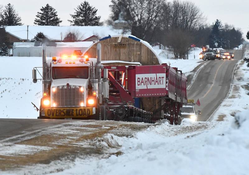 Two semi tractors pulling and pushing the trailer carrying a large turbine for Constellation's Byron generating station head north on German Church Road en route to the nuclear power plant on Monday, Dec. 8, 2025.