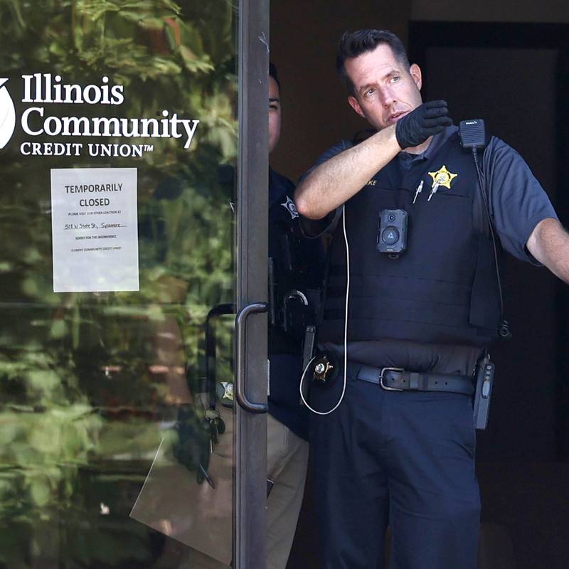 DeKalb Police officers look out the door of the Illinois Community Credit Union Wednesday, July 31, 2024, as they investigate a morning bank robbery in the facility at 1500 Barber Greene Road in DeKalb.