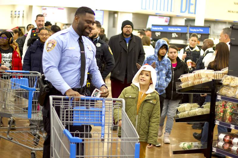 Joliet Police Officer James Williams (left) prepares to shop with a child during the 36th annual Santa's Cops event on Saturday, Dec. 6, 2025, at Walmart, 401 Illinois Route 59, in  Shorewood.