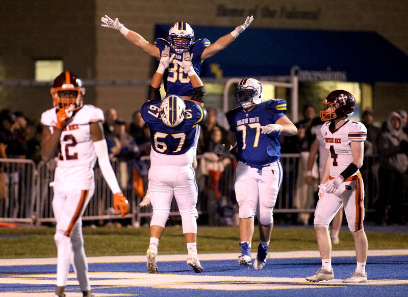 Wheaton North's Luke Beedle (30) is hoisted up by teammate Caleb Varney (67) after a touchdown during a Class 7A semifinal against Brother Rice at Wheaton North on Saturday, Nov. 20, 2021.