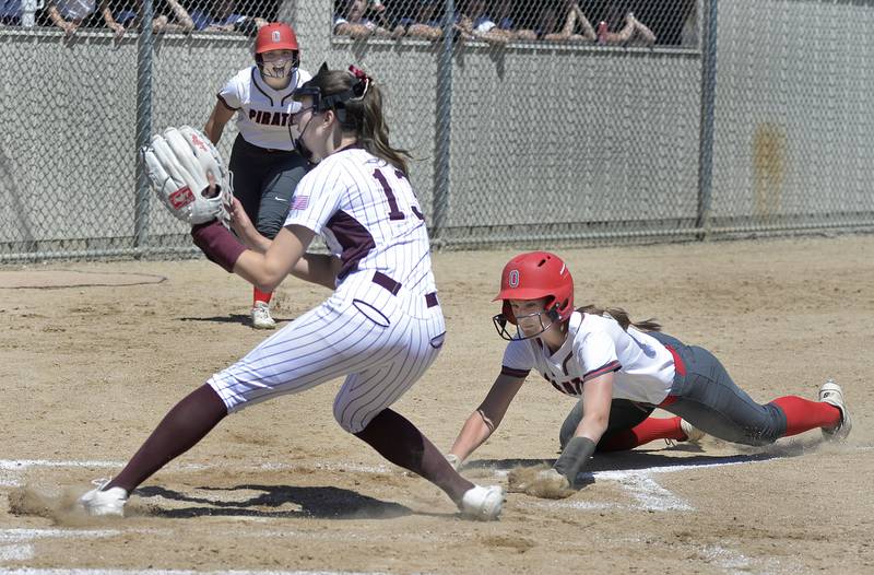 Morris starting pitcher Tess Shannon (13) waits for the throw from the backstop after a wild pitch as Ottawa’s Hailey Larsen slides safely into home to score in the first inning of the Pirates' regional championship win Saturday, May 25, 2024, at King Field in Ottawa.
