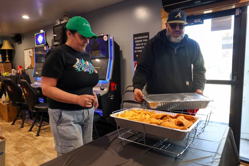 Manager Amanda Jolly, left, receives a donated meal from Marques Covington, owner of Mac’s BBQ Food Truck, at the Fun Hub on March 12, 2026. The small bar transformed into a bustling hub of supplies, food and resources following the March 10 tornado that caused destruction in Aroma Township and across Kankakee County.