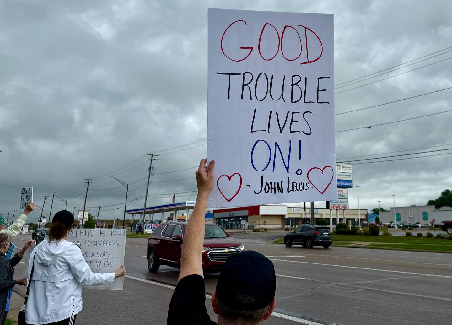 Protestors gather on Saturday, July 19, 2025, along Sycamore Road in Hopkins Park in DeKalb for a "Good Troubles Lives On" demonstration, one of thousands organized this week to honor the life and legacy of the late U.S. Rep. John Lewis. Though the official event was canceled due to weather Saturday, many still showed up to protest actions taken by President Donald Trump and his administration.