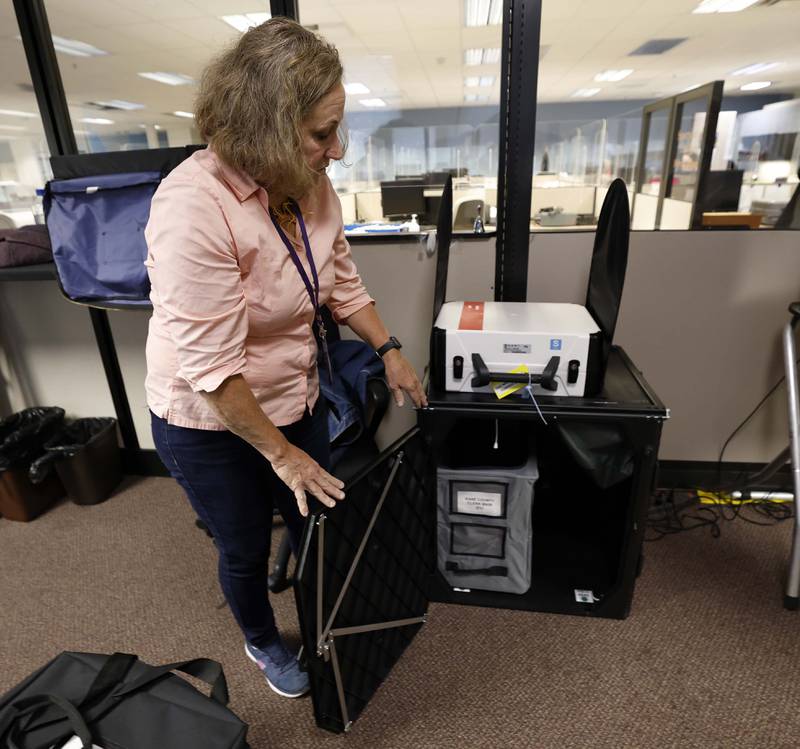 Lauren Behnke Warehouse Coordinator for the Kane County Clerk explains how the ballot is scanned into the white machine and then dropped into this secure cabinet while setting up for early voting machines Tuesday, Sept. 24, 2024 in Geneva.
