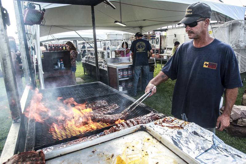 Texas Outlaw employee Ron Godsey of Elizabethtown, Kentucky, flips the ribs while grilling Thursday, July 11, 2013, at the Lake in the Hills Rockin' Ribfest at Sunset Park.