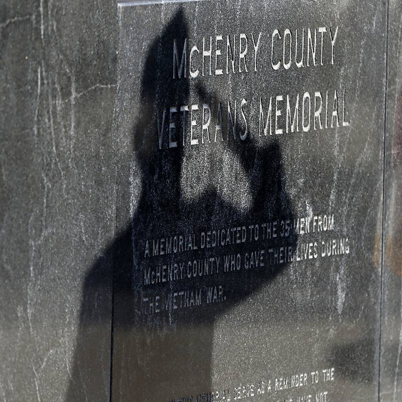 Veteran Carl Kamlenski’s shadow is cast onto the McHenry County Veterans Memorial as he salutes McHenry County veterans who died in the Vietnam War during the “Voices from Vietnam,” program on Friday, March 29, 2024, at the McHenry County Government Administration Building in Woodstock. The program was the first time that McHenry County honored Vietnam veterans on Vietnam War Veterans Day. The day, that was created by federal law enacted in 2017, honors the more than 2.7 million American men and women who served in Vietnam. The way the shadow seems to come out of the stone bringing the memories of fallen soldiers to life.