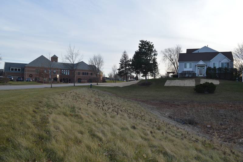 The village of Algonquin, whose police department building is seen at left, is in the midst of a legal fight over its attempted purchase of a vacant drainage area behind homes like the one seen at right in the Dawson Mill Village Condo Association.