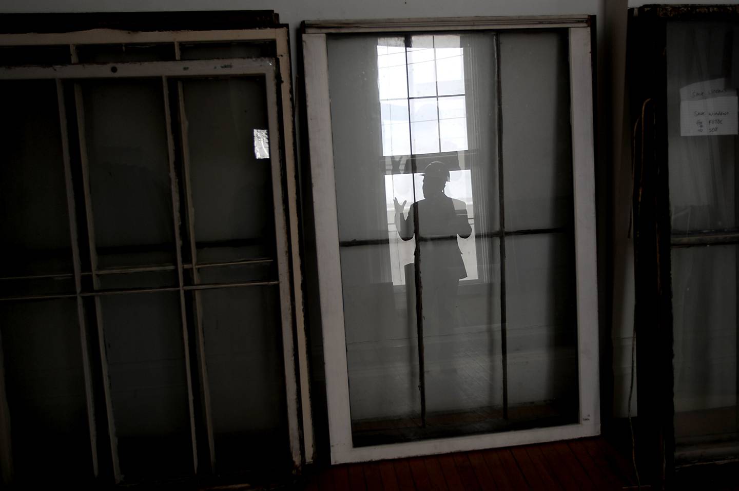 Woodstock City Planner Darrell Moore is reflected in old windows as workers from Bulley & Andrews, a Chicago-based contractor, work on the Old Courthouse and Sheriff’s House in Woodstock on Tuesday, March 1, 2022.