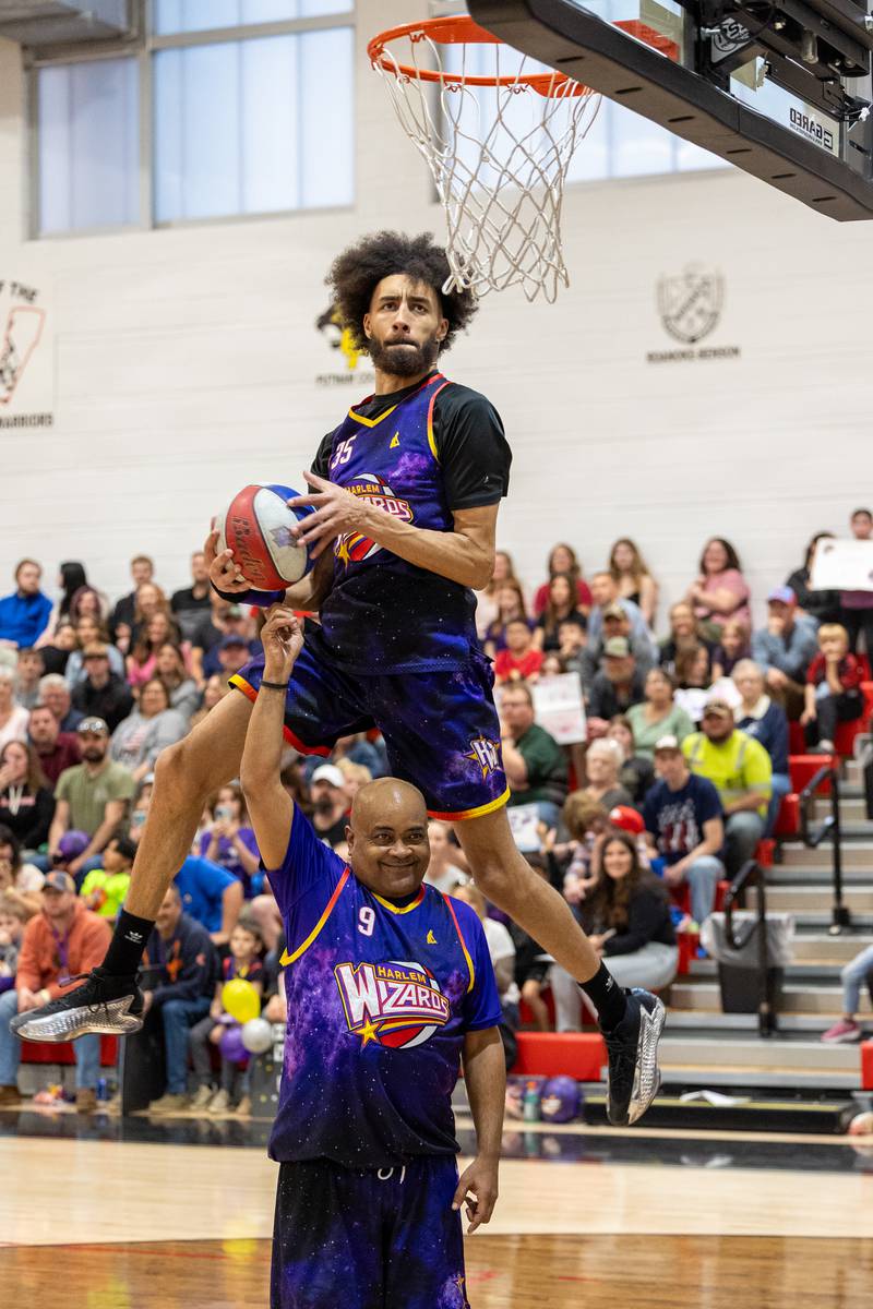Tyler “Sky-Rise” Cronk (35) of the Harlem Wizards dunks over teammate Arnold “A-Train” Bernard (9) on Wednesday, April 16, 2025 at Woodland High School in Streator.