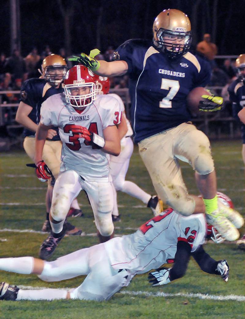 Marquette's Curtiss Johnson leaps over Forreston's Robert DeVries on a run in the third quarter of Saturday's Class 1A second round playoff game. Johnson is one of four seniors and one junior who were members of Marquette's 0-9 team in 2010.