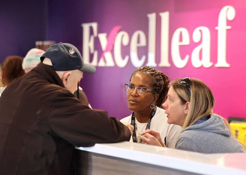 One of the Excelleaf owners Maria Davis (middle) and budtender Jamie Cardenaz help customer Steve Guadagnoli, 79, of DeKalb, Friday, Nov. 24, 2023, during the soft opening of the dispensary in DeKalb. The business is DeKalb County’s first recreational marijuana dispensary.