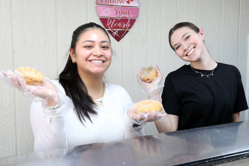 Patrica Madrigal and Shechinah Ridley pose for a photo while they hold Paczki's at the Spring Valley Bakery on Tuesday, Feb. 13, 2024 downtown Spring Valley. A Paczki is a popular Polish-American tradition where bakeries make doughnuts filled with jelly and coated in sugar. The tradition is popular in the Illinois Valley for a Fat Tuesday feast.