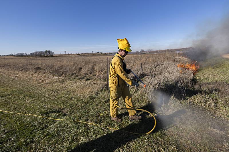 Riley Berner puts down a wet line Tuesday, Nov. 14, 2023 to keep the fire in line.