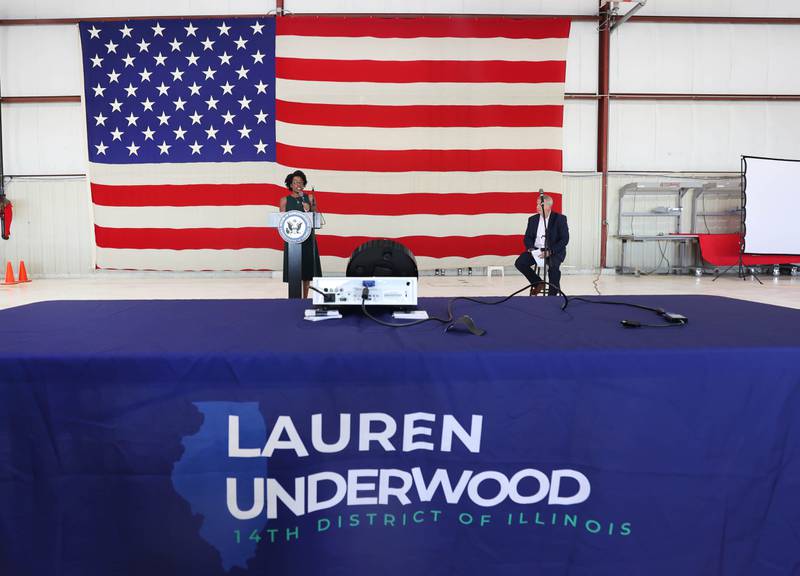 U.S. Rep. Lauren Underwood, D-Naperville, speaks in front of a large American Flag as DeKalb mayor Cohen Barnes looks on Tuesday, Aug. 23, 2022, during a town hall meeting in one of the hangers at the DeKalb Taylor Municipal Airport.