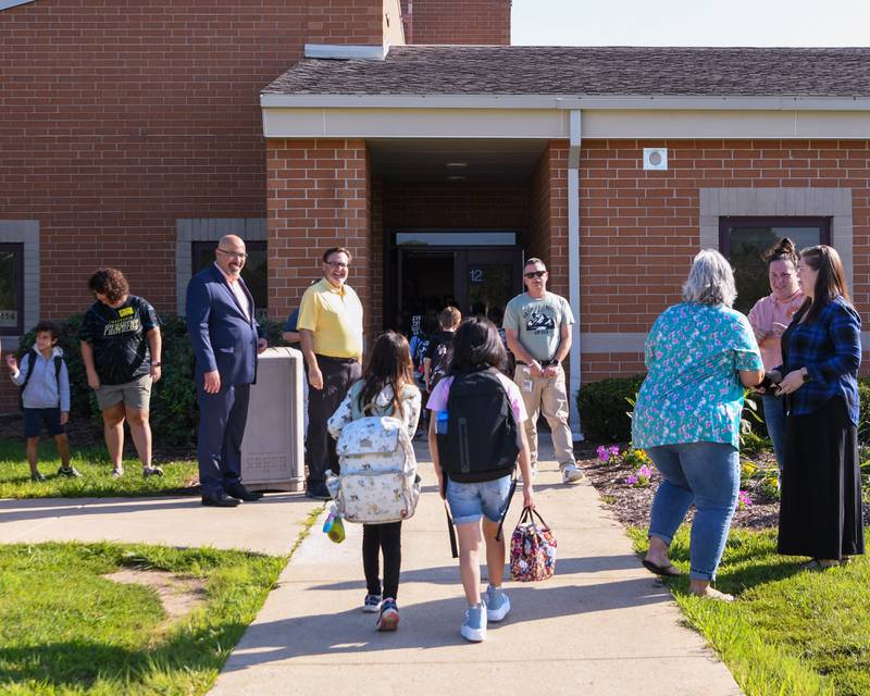 Students enter Fox Chase Elementary as they are welcomed by Oswego school board superintendent Andalid Khelghati, left, school board member Dominick Cirrone, center, and Fox Chase principal Jeff Renaldi during the first day of classes on Wednesday Aug. 16, 2023.