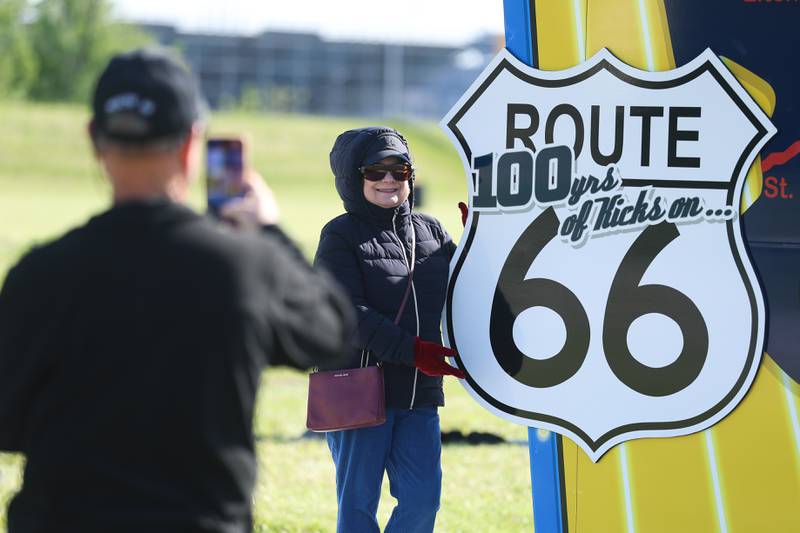Tim Shanahan takes a photo of his wife Mary Lou in front of the new Route 66 sculpture along South Chicago Street at the Route 66 Raceway on Tuesday, May 12, 2026 in Joliet.