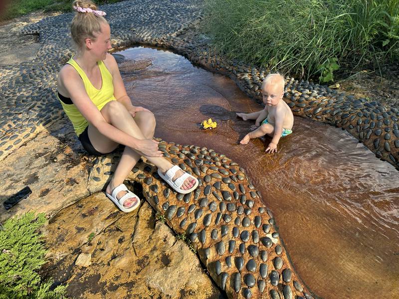Bensyn Engelbarts, 1, of Forreston, cools off with his mom, Karissa, in the "river" at the Oregon Park District's Splash Park on Monday, July 28, 2025. The free splash park is located in Oregon Park West.