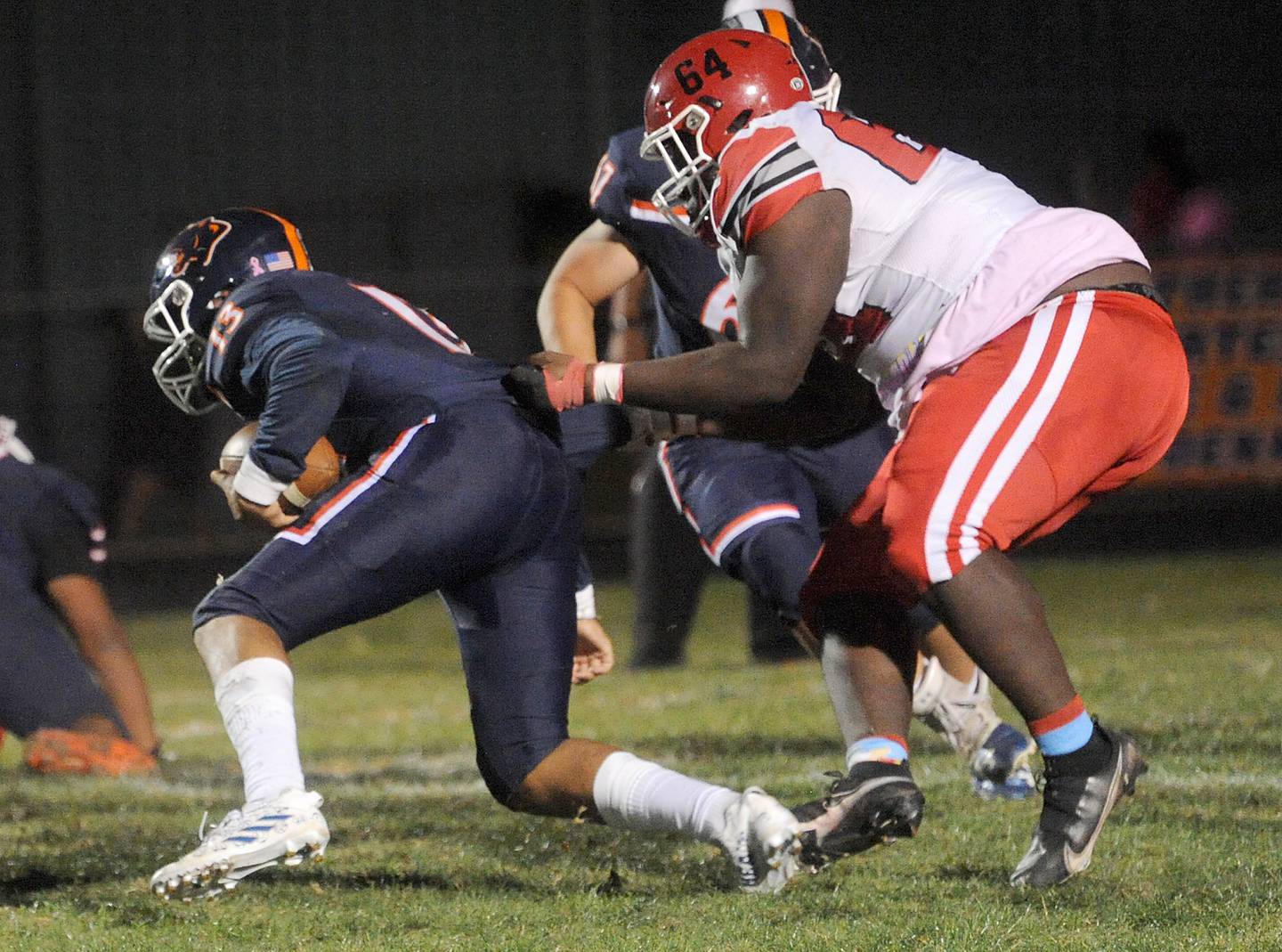 Yorkville defensive lineman Amani Kortie (64) sacks Oswego quarterback Cruz Ibarra by the shirt tail during a varsity football game at Oswego High School on Friday, Oct. 21, 2022.