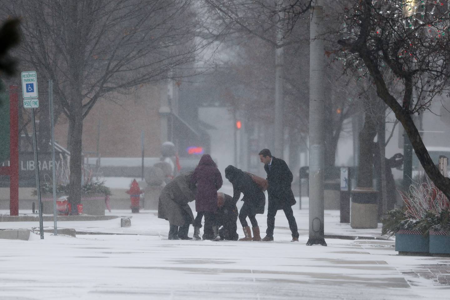 A group helps up a member of their party who slipped on the icy sidewalk along North Chicago Street in Downtown Joliet.