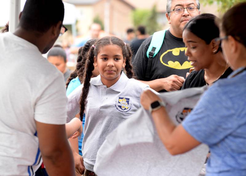 District 99 student Elizabeth Baez tries on her gym uniform shirt with the help of Assistant Superintendent, Mary Mycyk during the Back to School Fair held at the Cicero Community Park Sunday Aug 13, 2023.