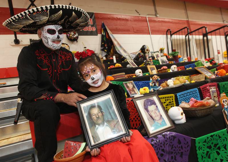Maya Juarez, 5, sits with her grandfather, Ricardo, both of Fox Lake as she holds a photo of her great, great grandfather, Nick Figueroa, and they both sit next to a photo of her great grandfather, Rufino, during the Dia de los Muertos, Day of the Dead event at Stanton Middle School on November 4th in Fox Lake. The event was sponsored by the Bilingual Parents Advisory Committee (BPAC) from School Districts 114,124 and 37.
Photo by Candace H. Johnson for Shaw Local News Network