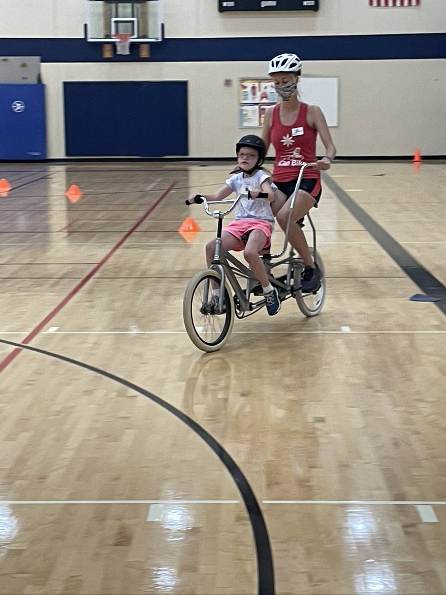 Faye Rossi, 8, of Manhattan practices riding a bike with the help of Kaityln Schmidt, floor supervisor for iCan Shine, Inc. The iCan Bike program, which teaches people with disabilities ages 8 and up to ride a conventional two-wheel bike, was held June 14 to June 18, 2021, at Spencer Crossing School in New Lenox.