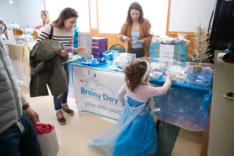 Kids looking at snow globe making table at  Frozen Fest at Maryknoll Park on Saturday, Jan. 11, 2025 in Glen Ellyn.