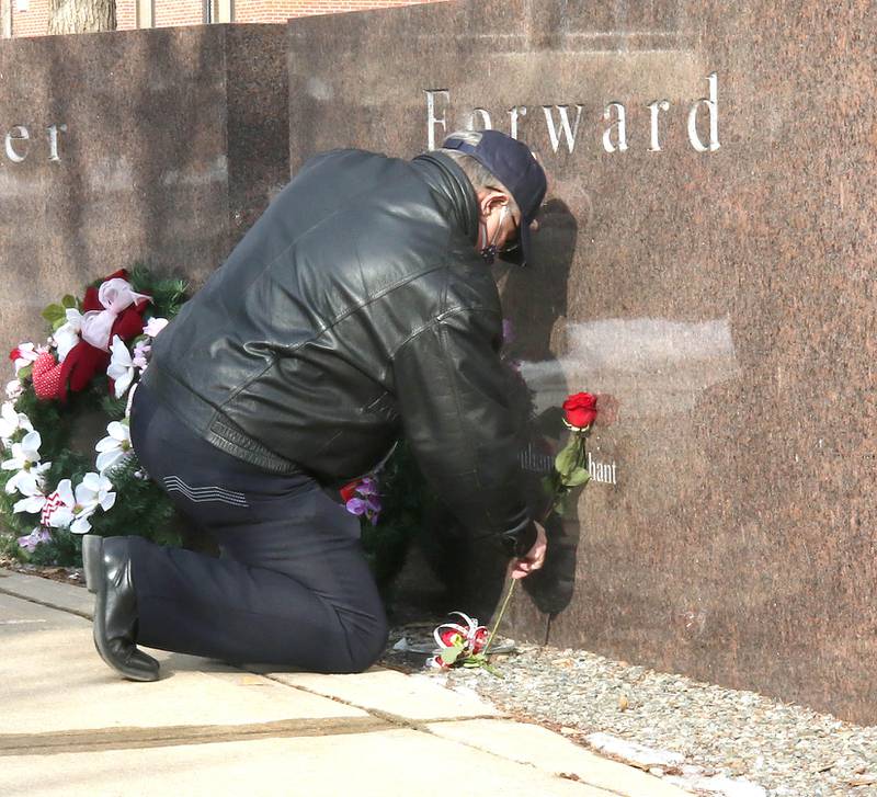 Larry Gehant adjusts the flowers on the stone that bears his niece, Julianna Gehant's, name Monday, Feb. 14, 2022, during a remembrance ceremony at the Forward, Together Forward marble memorial outside Cole Hall at Northern Illinois University in DeKalb. Monday marked the 14th year since the deadly shooting took place on campus which took the lives of five people.