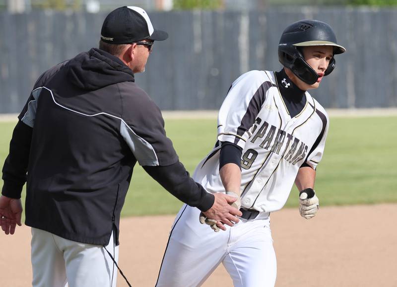 Sycamore's Jackson MacDonald is congratulated by head coach Jason Cavanaugh as he rounds third after homering Wednesday, May 13, 2026, during their game against Morris at the Sycamore Community Sports Complex.