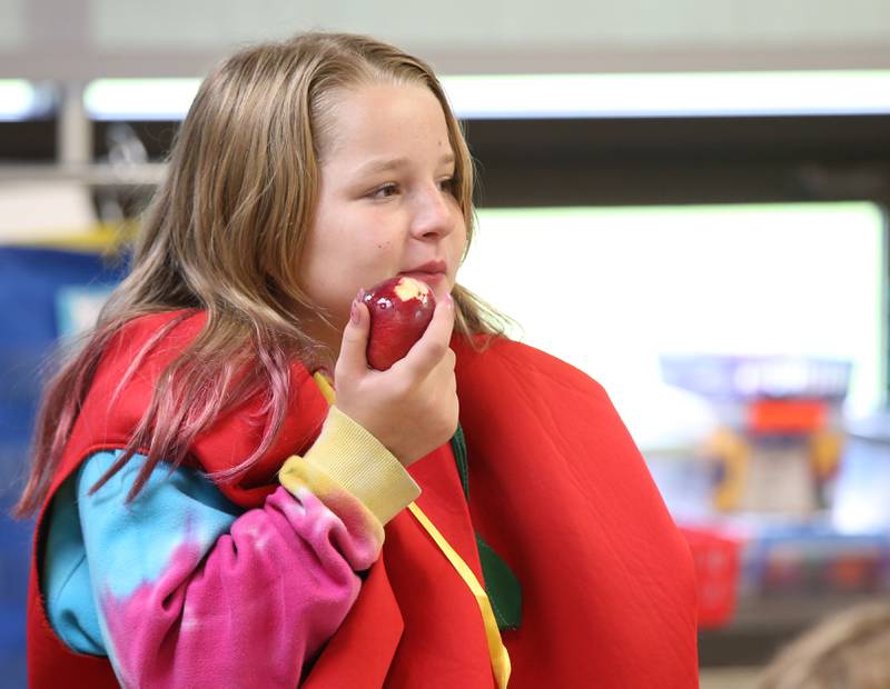 Lily Francis a student at Northwest Elementary School bites into a apple while wearing an apple costume during the Great Apple Crunch on Thursday, Oct,. 12, 2023 at Northwest School in La Salle. The Great Apple Crunch is an annual celebration of fresh, local apples on the second Thursday of October during National Farm to School Month. The apples were donated by Boggios Orchard and Produce.