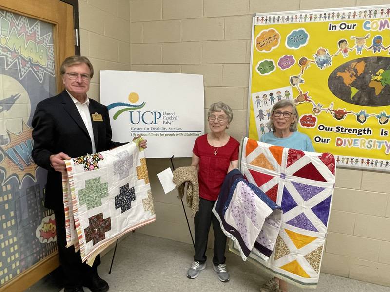 Members of the quilting club of Peace Lutheran Church in New Lenox donated more than 25 handmade, twin and full-sized quilts and prayer shawls to United Cerebral Palsy-Center for Disability Services in Joliet. Pictured, from left, are Mike Hennessy, executive director of UCP-CDS, and club members Karen Dircks and Syndy Lindbloom.