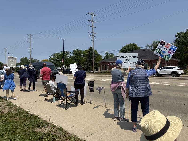 People hold up signs along Route 47  in Huntley during a rally against President Donald Trump May 31, 2025.