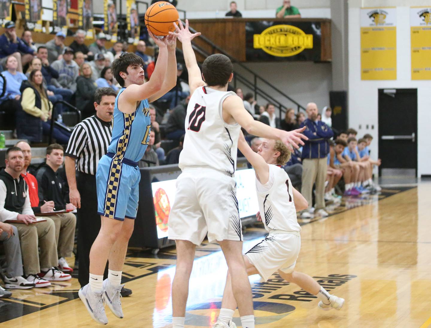 Marquette's Alec Novotney shoots a jump shot over Woodland's Jaron Follmer and Connor Dodge during the Tri-County Conference Tournament this past season at Putnam County High School.