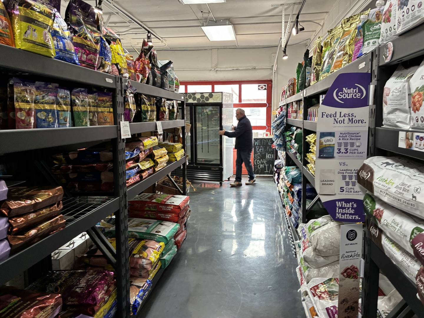 Scott Giles moves a for-sale refrigeration unit out of the way at Reeses Barkery and Pawtique on Wednesday, March 4, 2026. The Giles family is getting their pet emporium settled in at the temporary store, at 3314 Pearl St., McHenry, following a fire Jan. 18 at their Riverside Drive location.