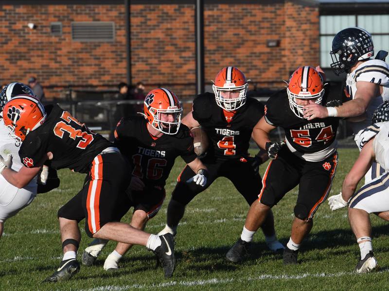 Byron's Dawson Criddle (4) looks for a hole as blockers Cade Considine (37),  Andrew Talbert (16), and Braiden Hammes (54) try and clear the path against Elmhurst IC Catholic on Saturday, Nov. 15, 2025. The Tigers won the game 28-6 to advance to the state semifinals.