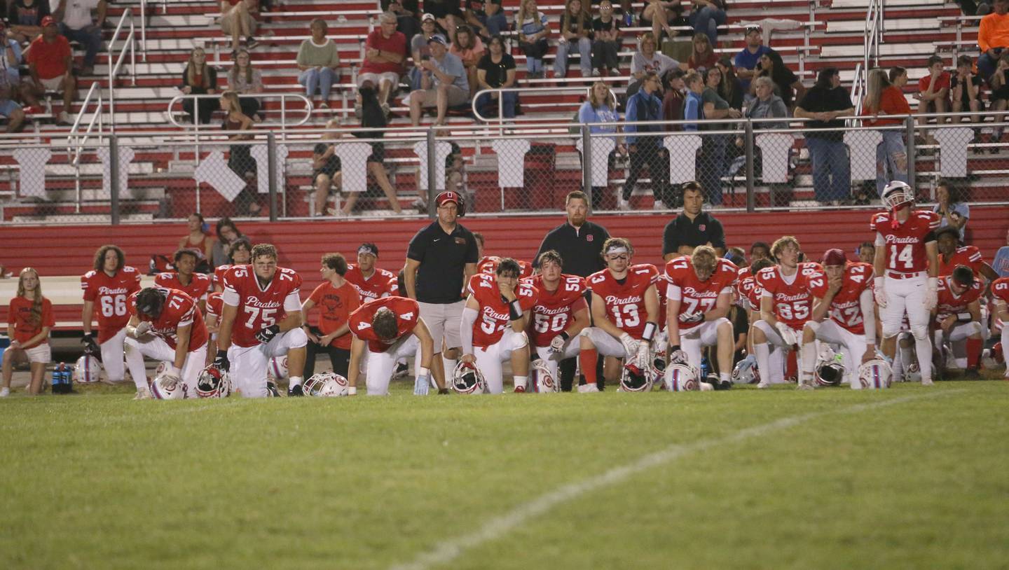 Ottawa football players take a knee as quarterback Mark Munson is carried off of the field by ambulance in the third quarter on Friday, Sept. 12, 2025 at King Field.