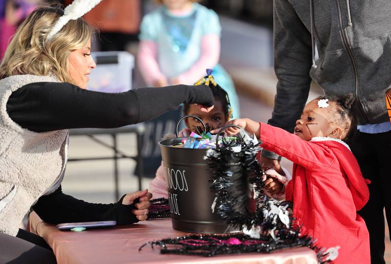 Naylahnii Young, 2, from DeKalb tells Gianna Burdick, manager of Canvas Hair Studio, what kind of candy she wants in front of the salon  on Lincoln Highway in downtown DeKalb Thursday, Oct. 27, 2022, during the Spooktacular trick-or-treating event hosted by the DeKalb Chamber of Commerce.