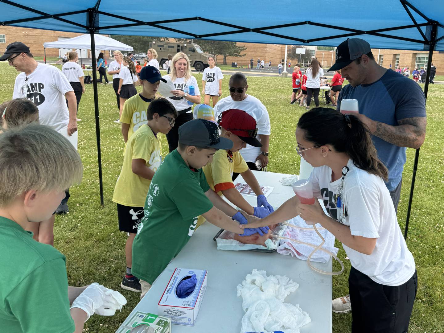 Vanessa Read (right) shows kids how to properly stop a wound from bleeding before showing them how to pack it with gauze on Friday, June 13, 2025.