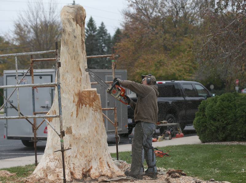Bud Hainzinger of Morris begins to carve a cross in a tree stump at St. Johns Lutheran Church on Friday, Nov. 3, 2023 in Peru. In May a storm blew done this tree. The tree was lopped off and from the remaining trunk a quote was done to carve a cross into it. The family of Don and Ruth Johnson donated the cost of the tree carving in memory of their parents.
