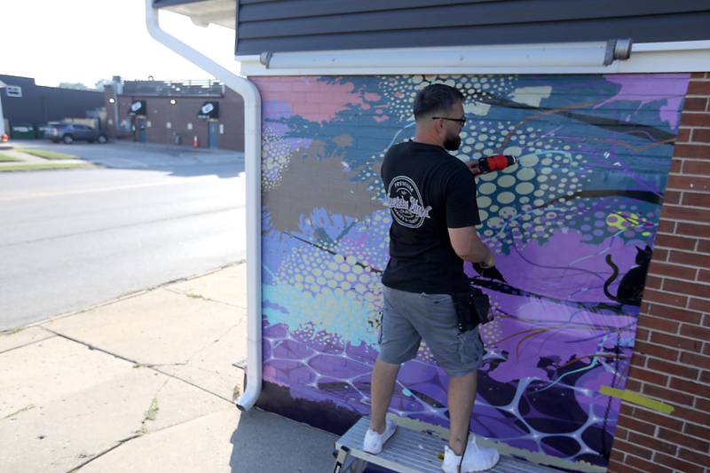 Mike Suchowski, of Invictus Vinyl, instals a new mural on Monday, Sept 15, 2025, on the side of a building at 3430 West Elm Street in McHenry.