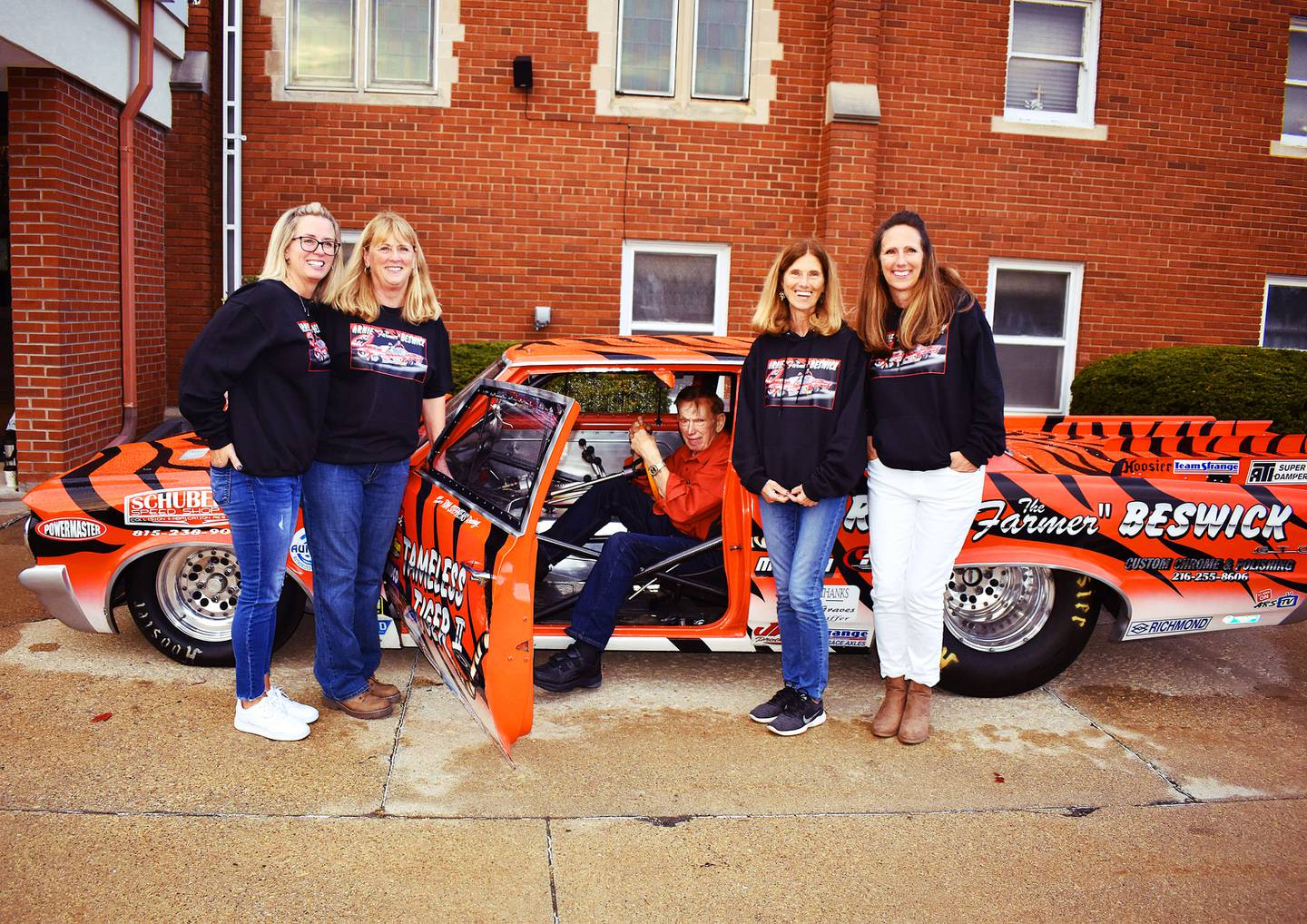 Arnie "The Farmer" Beswick, 94, of Morrison, sits in his dragster "Tameless Tiger II" outside the Ebenezer Reformed Church in Morrison during a Saturday, Nov. 9, 2024 event honoring his drag racing career. Pictured with Arnie are his daughters Rhonda, Paula, Arnette and Michele.
