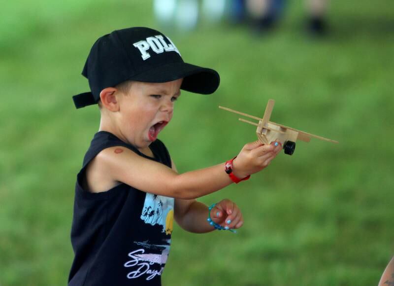 Rowan LaTessa, 4, of Wonder Lake takes a wooden toy plane for a test flight during Fiesta Days at Petersen Park in McHenry Sunday. LaTessa constructed the craft as part of a Home Depot  craft booth.