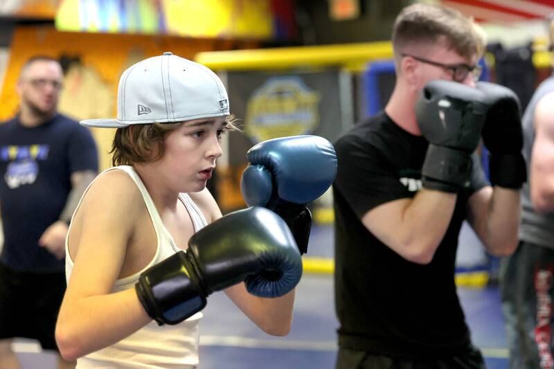 Viktor Hammon, (left) 14, from Sycamore, and Dylan Cranden, from DeKalb, punch the heavy bag during a class Thursday, Nov. 9, 2023, at Evolve MMA and Powerlifting in DeKalb.