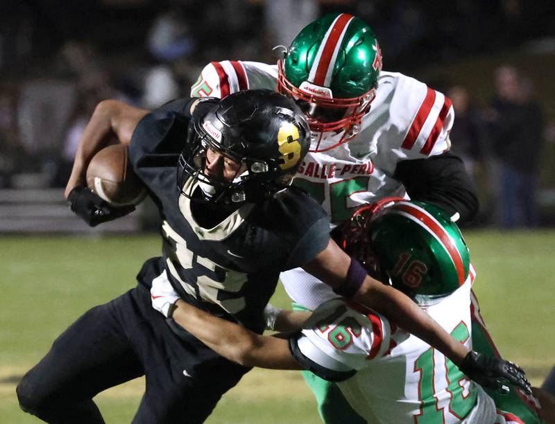 Sycamore's Dylan Curtis tries to pull away from La Salle-Peru’s Owen Mrowicki (left) and Evan Downey during their game Friday, Oct. 10, 2025, at Sycamore High School.