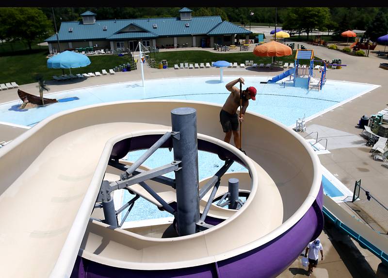 Lifeguard Jacob Brucker cleans a slide Wednesday, May 24, 2023, at the Woodstock Water Works Aquatics Center in Woodstock as the pool gets ready to open on Saturday.