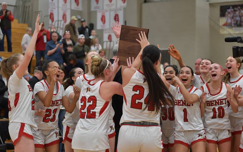 Benet’s Bridget Rifenburg (22) and Emma Briggs present the championship plaque to their teammates after the Class 4A Benet Regional final against Oswego East on February 19, 2026 at Benet Academy in Lisle.