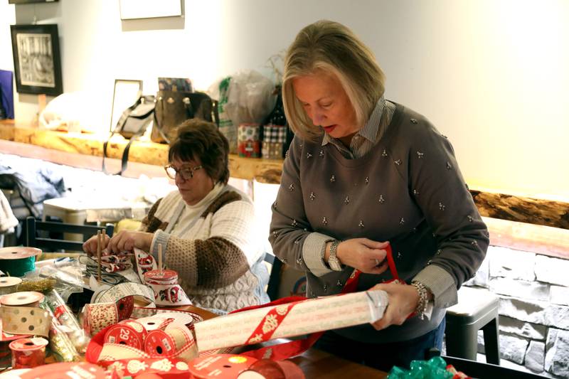 Michelle Lage applies a bow to a wrapped gift during a gift wrapping party for clients of the Association for Individual Development (AID) hosted by the Batavia Rotary Club on Thursday, Dec. 12, 2024 at Brother Chimp Brewing in North Aurora.