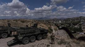 A man is halted climbing the US-Mexico border wall. Under new Trump rules, US troops sound the alarm